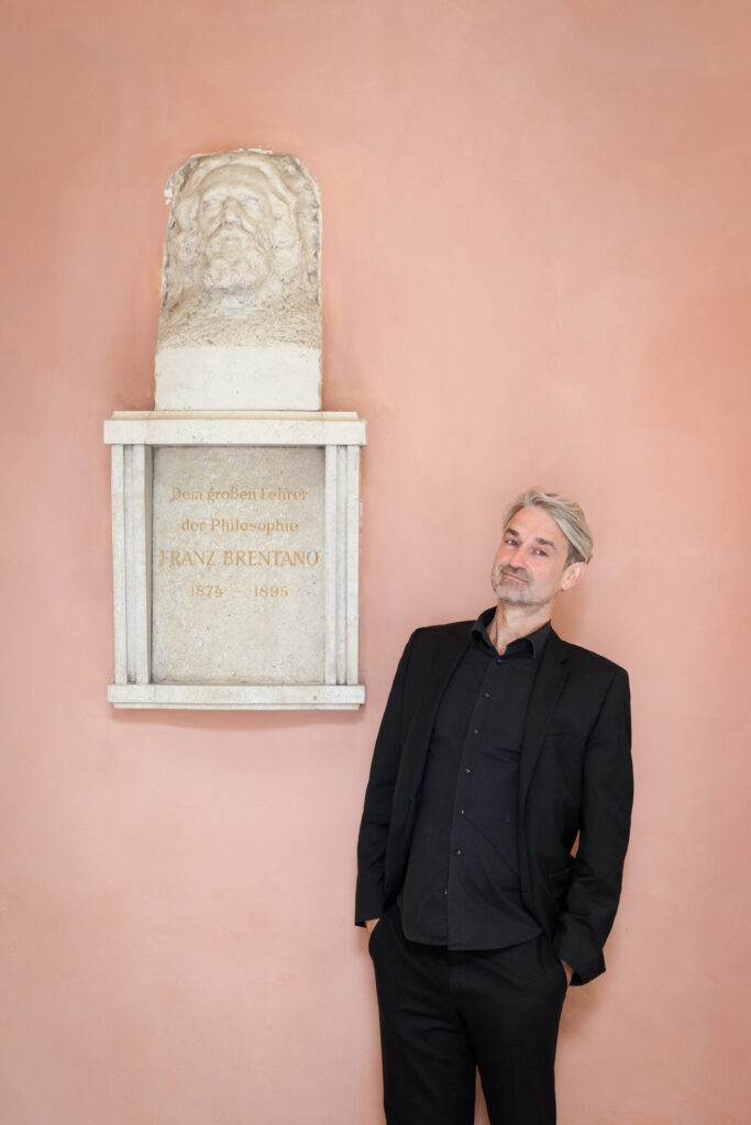 portrait Hans Bernhard Schmid next to a statue
